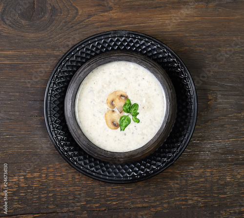 Champignon mushroom cream soup in bowl on wooden background. Rustic style. Top view.
