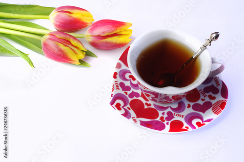 Tea for Two. Two cups of tea and a bouquet of red tulips