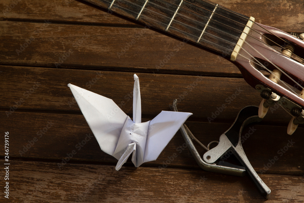 Paper bird with guitar and musical instrument on wooden table