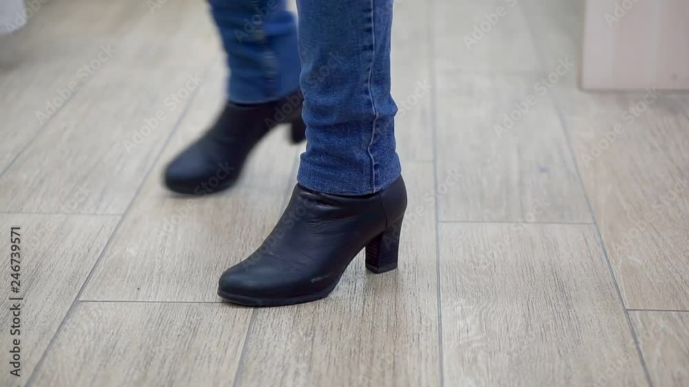 Woman in a clothing store, in a fitting room, close-up legs in jeans Woman in a clothing store, in a fitting room, close-up legs in jeans