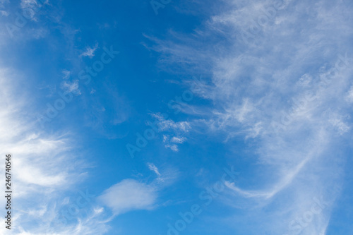 White cirrus clouds in the blue sky on a clear day in the summer. Used as a background image.