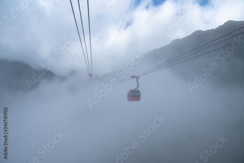 The cable car to mountain top with low clouds and mountain view