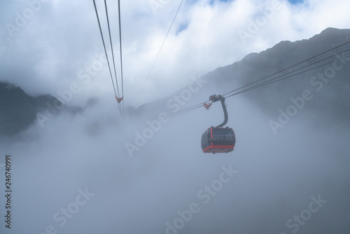 The cable car to mountain top with low clouds and mountain view