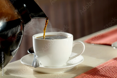 Morning of a new day, hand of young man hold coffee cup cappucino and he drink coffee on the wooden table at home