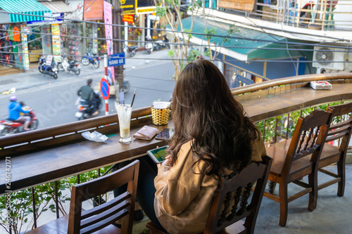 Young girl sitting in the open cafe with Hanoi street on background in Hanoi city, Vietnam