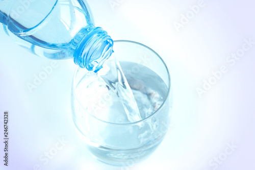 Pour pure water from a bottle of mineral water into a glass.