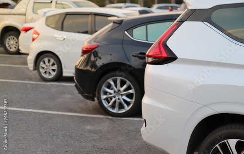 Closeup of back or rear side of white car and other cars parking in parking area in the evening of sunny day. 