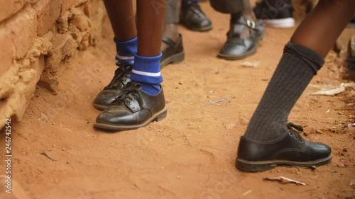 Rural African school pupils' shoes in the soil as they step forward in a line photo