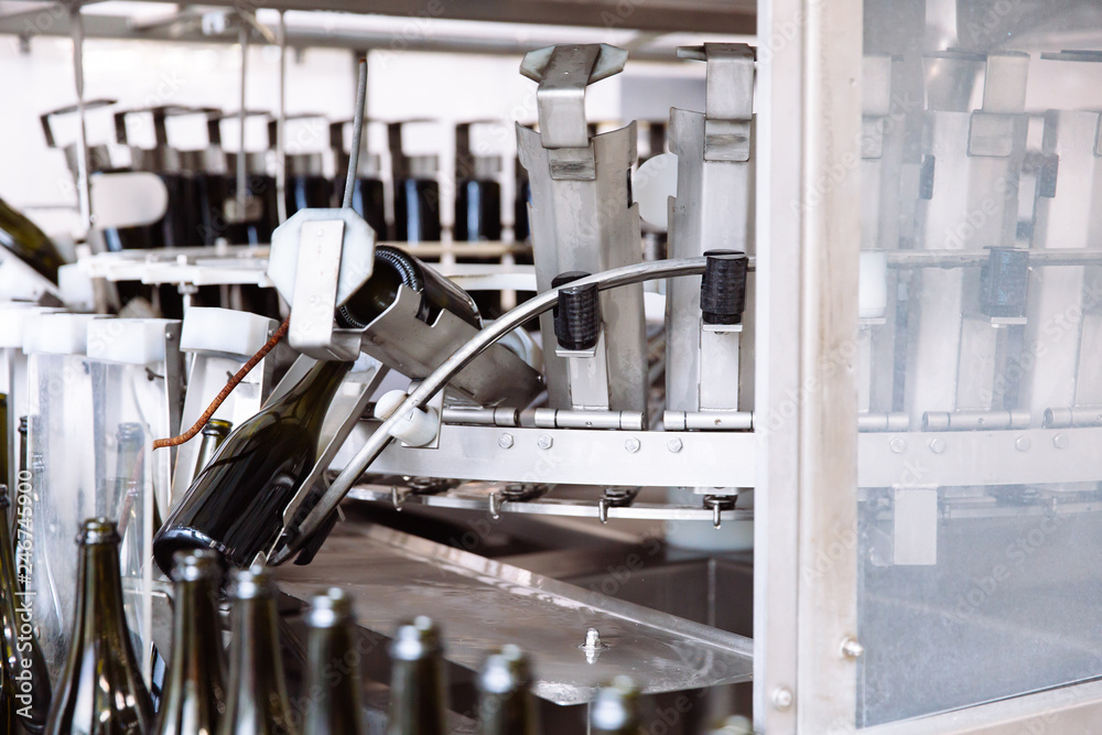 Glass bottles on the automatic conveyor line at the champagne or wine factory. Plant for bottling alcoholic beverages.