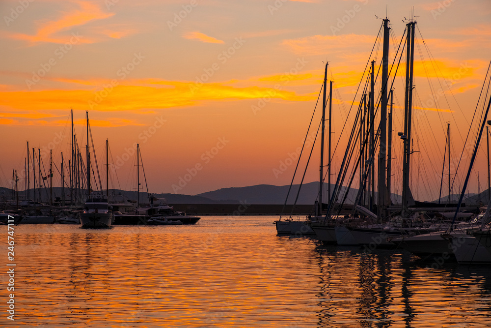 Alghero, Sardinia, Italy - Summer sunset skyline over the Alghero Marina yacht port at the Gulf of Alghero at Mediterranean Sea