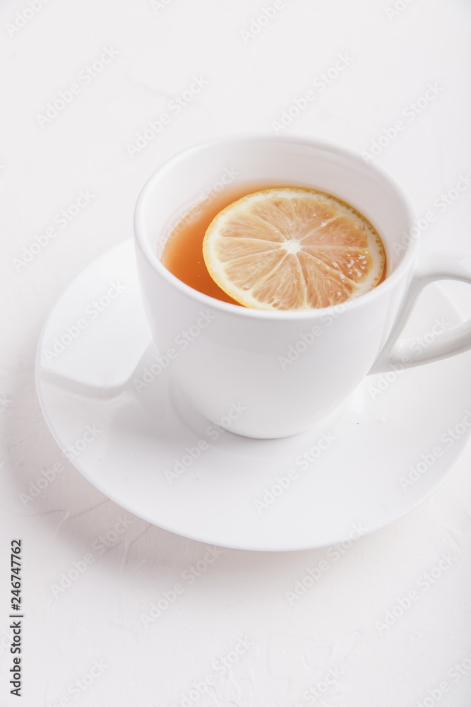 White cup with saucer with tea and lemon on white background. Copy space