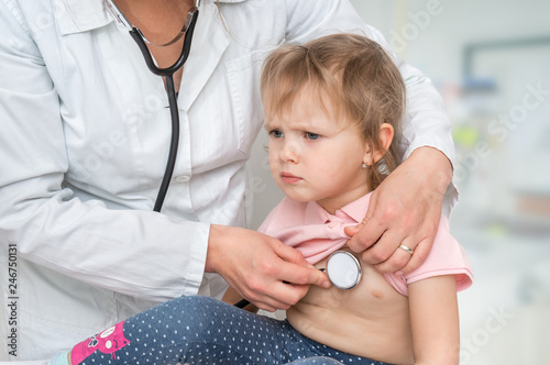 Pediatrician doctor examining a little girl by stethoscope