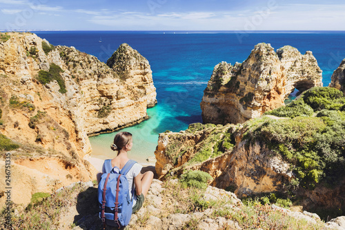 Young woman traveler looking at the sea in Lagos town, Algarve region, Portugal. Travel and active lifestyle concept