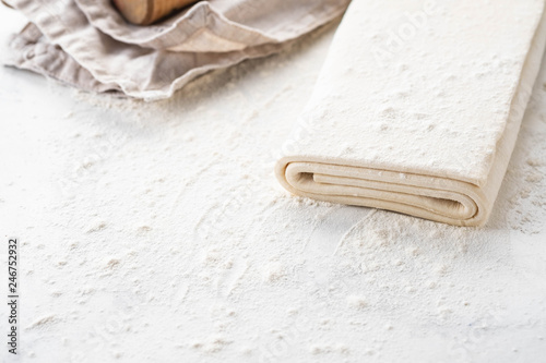 Homemade raw puff pastry on a white background.