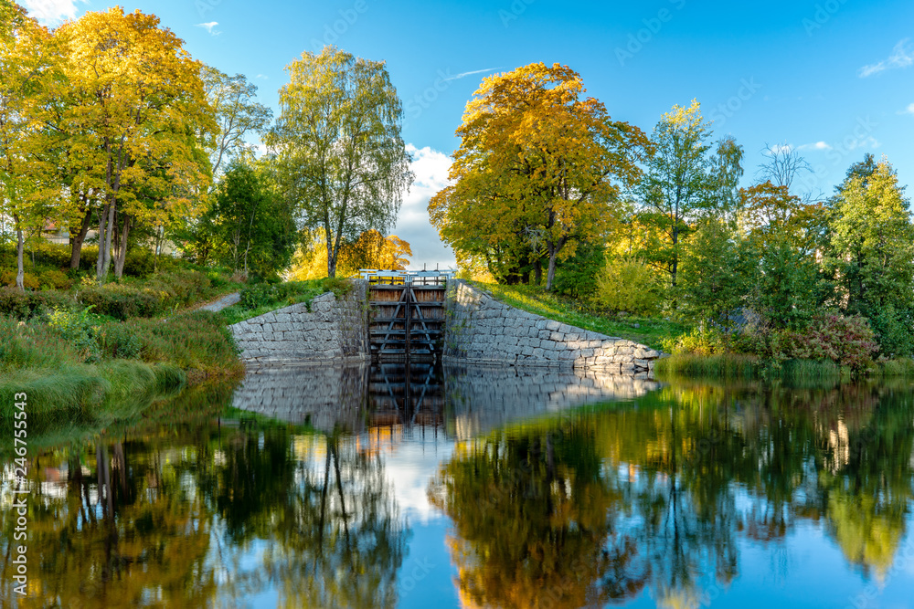 Obraz premium Colorful autumn view of a canal lock with smooth mirror like water