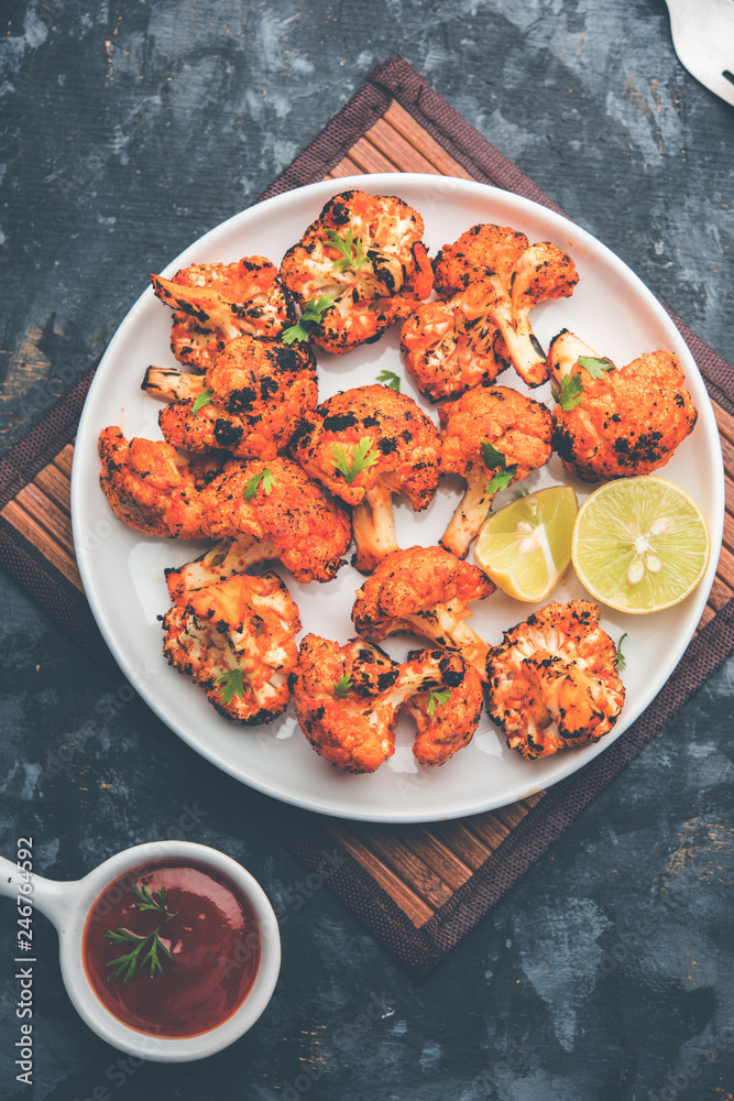 Tandoori Gobi / Roasted cauliflower Tikka is a dry dish made by roasting Cauliflowers in Oven/Tandoor. It's popular starter food from India. served with ketchup. selective focus Tandoori Gobi / Roasted cauliflower Tikka is a dry dish made by roasting Cauliflowers in Oven/Tandoor. It's popular starter food from India. served with ketchup. selective focus