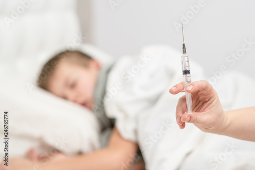 Close up view of a syringe with a child at the background