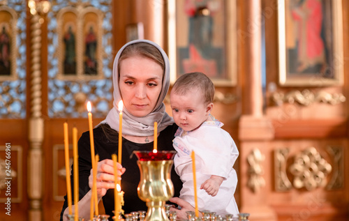 Fotografija a woman with a baby puts a candle in church