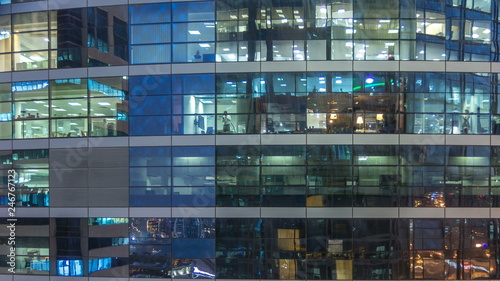Photography Glowing windows in multistory modern glass and metal office building light up at night timelapse