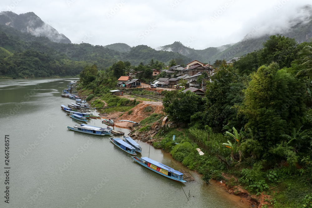 Naklejka premium Nong Khiaw is a village in a steep limestone cliff valley covered with jungle in the Luang Prabang Province of northern Laos. It's on the Nam Ou River, where tour boats and kayaks travel.