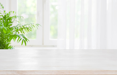 Wooden table top on blurred background of half curtained window