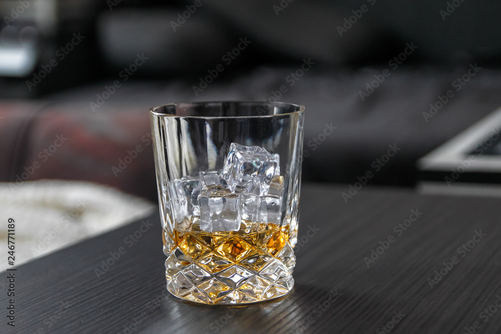 Glass of whiskey with ice cubes on black table Glass of whiskey with ice cubes on black table