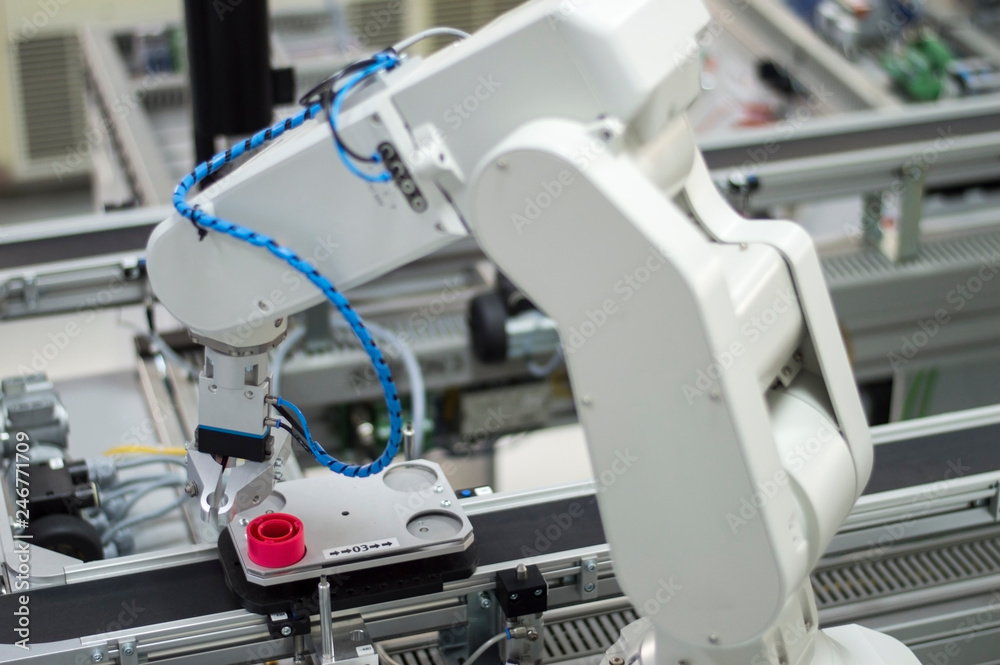 Focus on robotic arm's gripper. Industry 4.0 concept; artificial intelligence in smart factory. Robot picks up the product from automated car on the manufacturing line. Selective focus. Focus on robotic arm's gripper. Industry 4.0 concept; artificial intelligence in smart factory. Robot picks up the product from automated car on the manufacturing line. Selective focus.