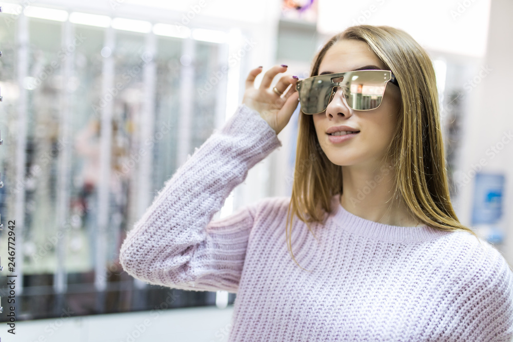 Happy young woman buying sunglasses in shop. Happy young woman buying sunglasses in shop.