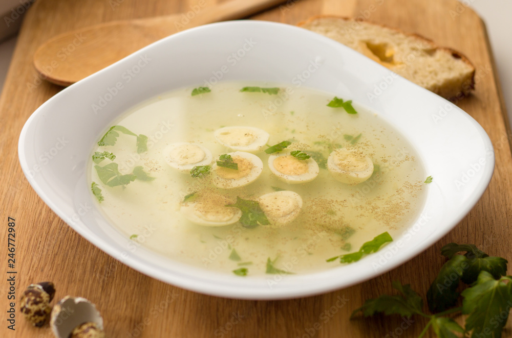 clear meat (chicken) broth with cut quail eggs, spices and greenery