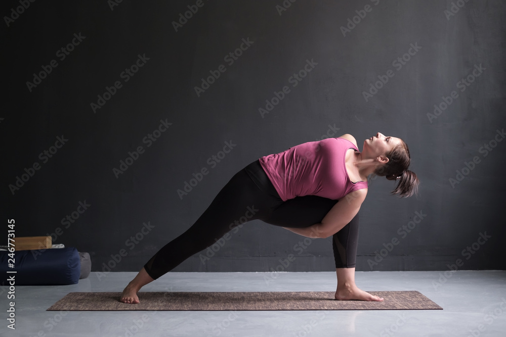 Woman practicing yoga Utthita parsvakonasana exercise, Extended Side Angle pose
