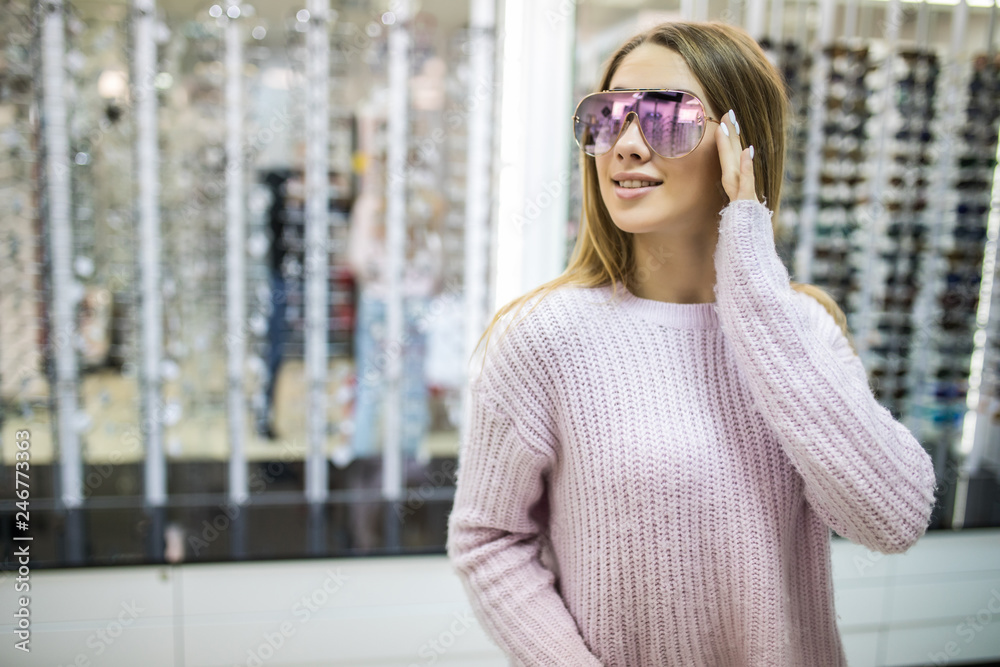 Pretty young woman shopping for sunglasses at the optometry store Pretty young woman shopping for sunglasses at the optometry store