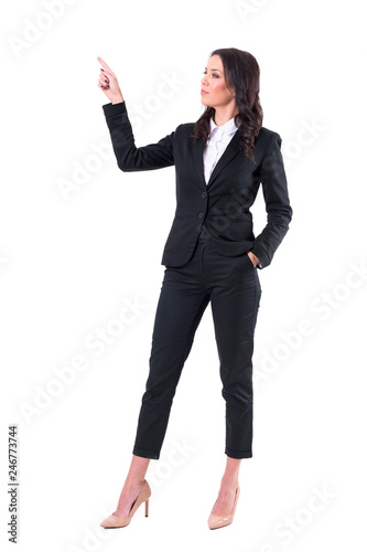 Elegant female business presenter in suit pointing finger up showing copy space. Full body isolated on white background. 