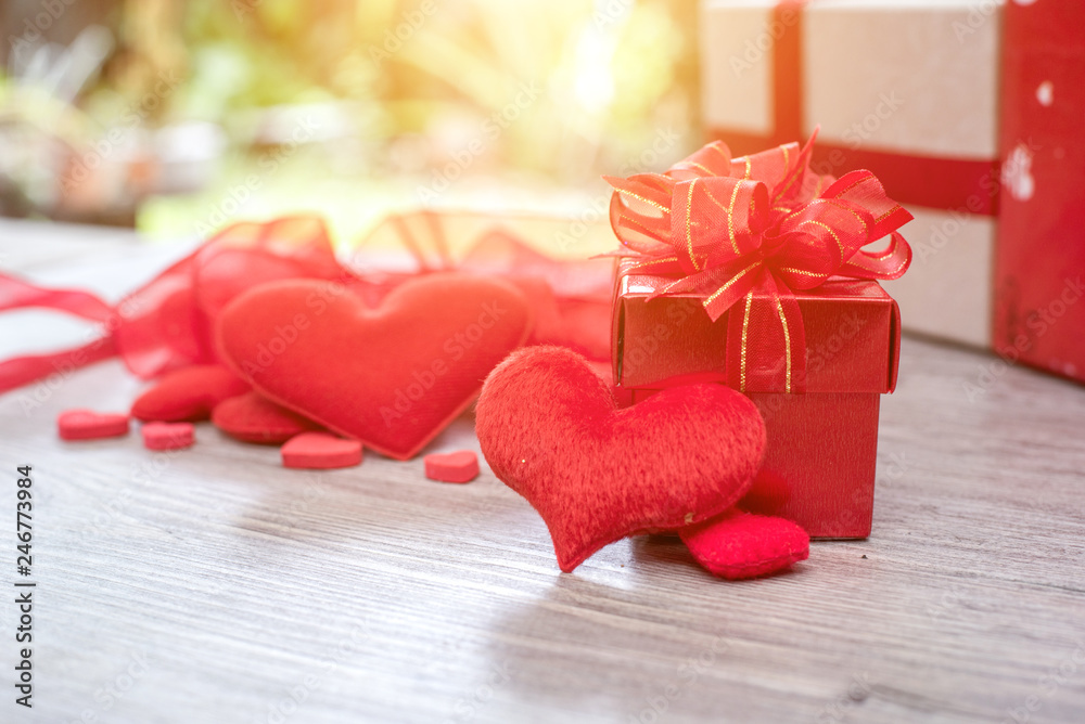 Fototapeta premium Gift box with red bow ribbon and paper heart on wooden table for Valentines day.