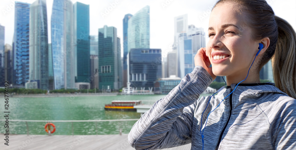 Fototapeta fitness, sport i ludzie pojęcie - szczęśliwa kobieta słucha muzyki w słuchawkach nad Singapore marina miasta tłem