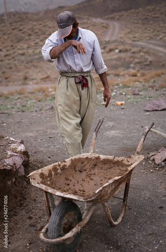 Tired construction worker with a wheelbarrow in Iran