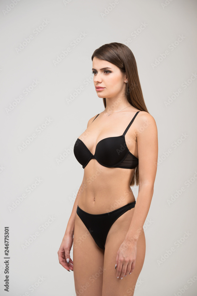 Three-quarter portrait of beautiful brunette women with a slim figure in  black bra and thong. Model snaps in the studio on white background Stock  Photo