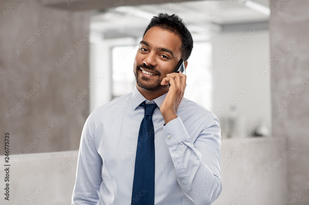 business, communication and people concept - smiling indian businessman calling on smartphone over office background business, communication and people concept - smiling indian businessman calling on smartphone over office background