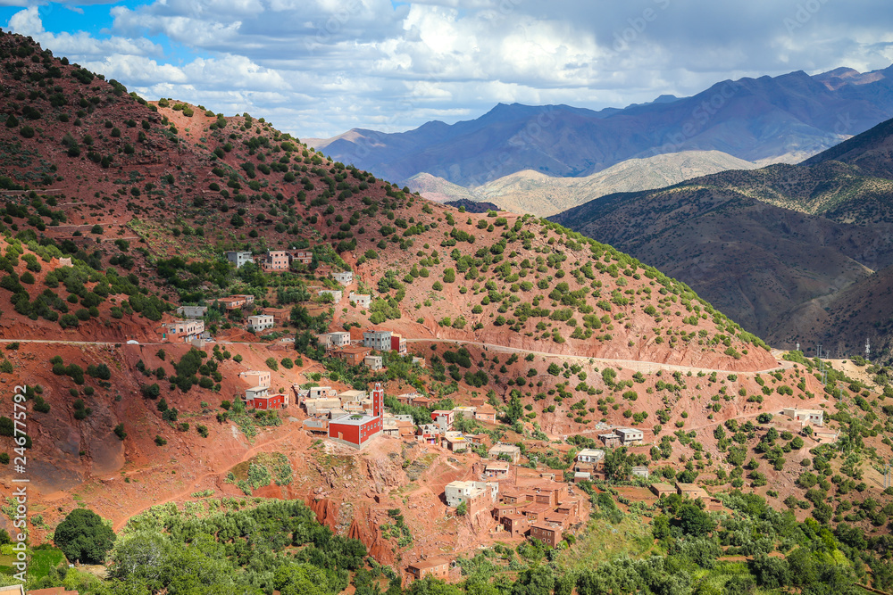 Atlas Mountain landscape in Morocco with a lush green valley, a village with old rock houses and green olive trees, near Ouarzazate