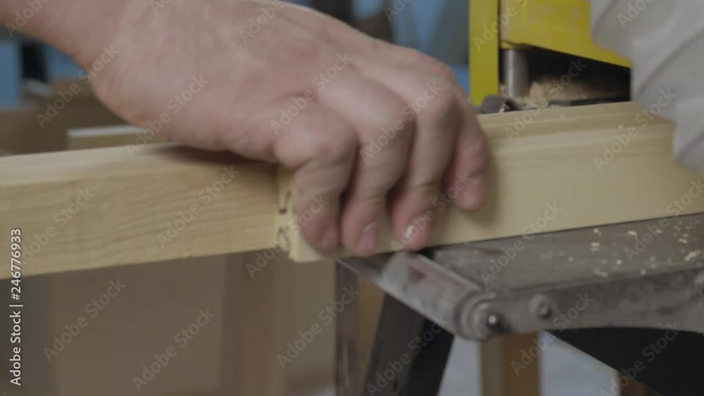Worker in safety glasses doing works in his workshop on woodworking machine