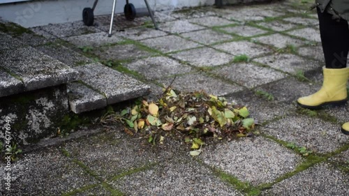 Wallpaper Mural A woman in yellow boots sweeps autumn leaves. Torontodigital.ca
