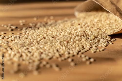 Raw Brown Rice On A wooden table With Bag In The Background. Organic Brown Rice On A table.