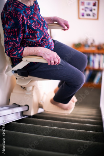 Detail Of Senior Woman Sitting On Stair Lift At Home To Help Mobility