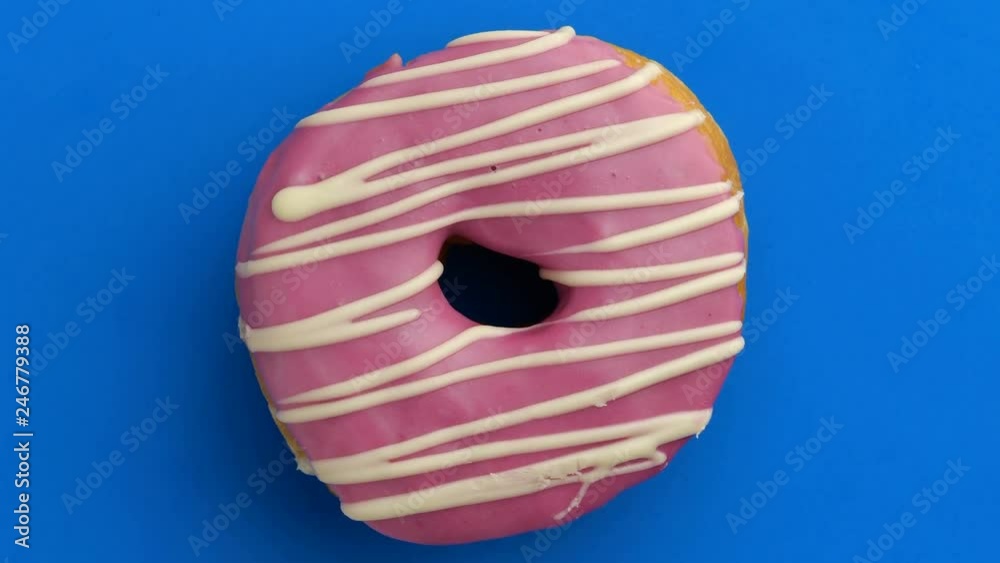 Bright and colorful sprinkled donut close-up shot spinning on a color background. Top view. Seamless looping. Bright and colorful sprinkled donut close-up shot spinning on a color background. Top view. Seamless looping.