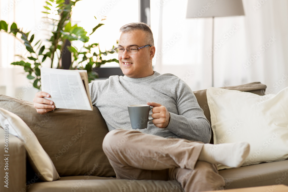 leisure, information, people and mass media concept - man reading newspaper and drinking coffee at home leisure, information, people and mass media concept - man reading newspaper and drinking coffee at home