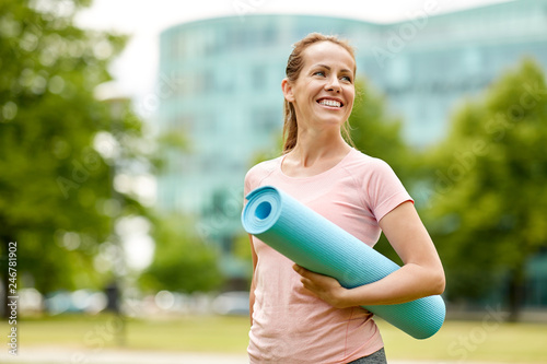 Fototapeta Naklejka Na Ścianę i Meble -  fitness, sport and healthy lifestyle concept - happy smiling woman with exercise mat at city park