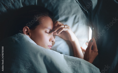 Woman in bed at night with smartphone