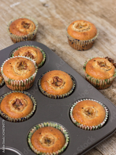 Homemade banana chocolate muffins in a baking form on a wooden background
