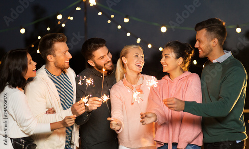 leisure, celebration and people concept - happy friends with sparklers at rooftop party at night © Syda Productions
