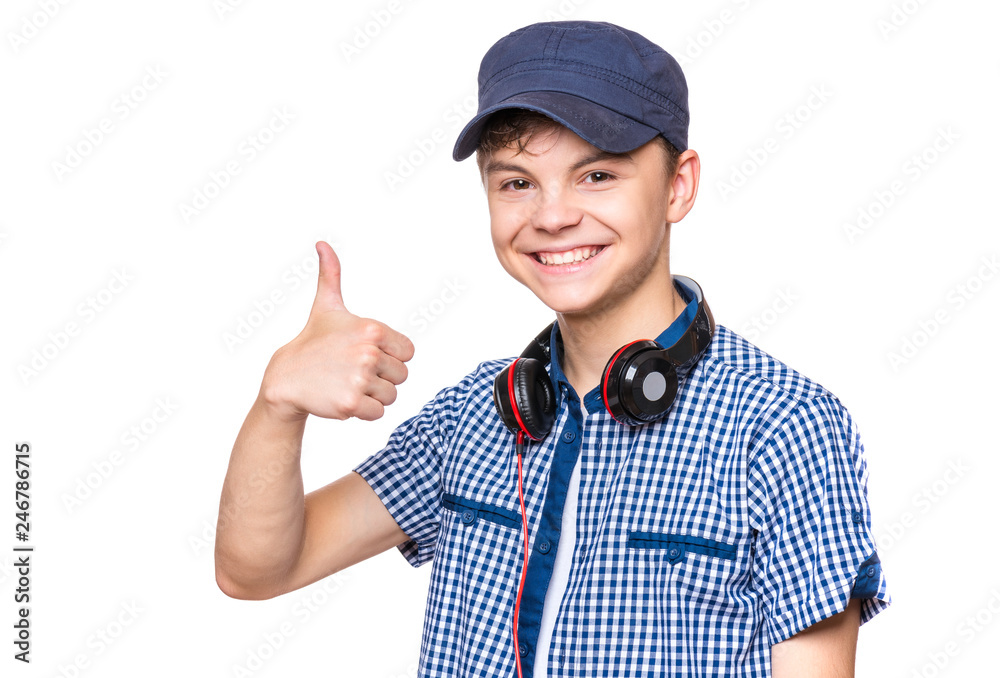 Portrait of young student with cap and headphones. Teenager smiling, making thumb up gesture and looking at camera. Happy teen boy, isolated on white background. Portrait of young student with cap and headphones. Teenager smiling, making thumb up gesture and looking at camera. Happy teen boy, isolated on white background.