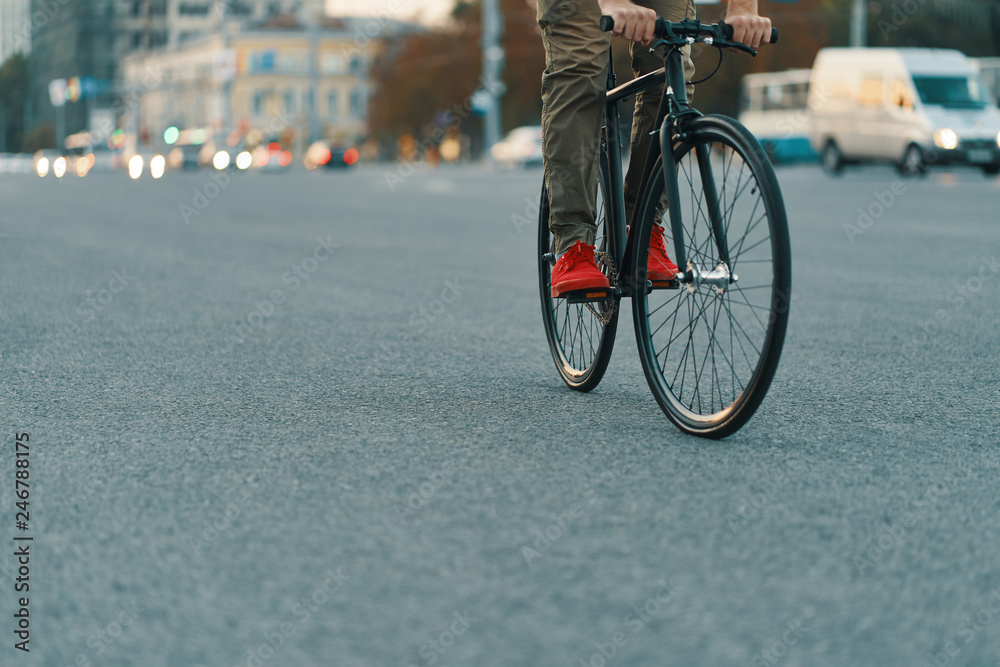 Closeup of casual man legs riding classic bike on city road Closeup of casual man legs riding classic bike on city road